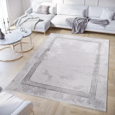 A modern living room with a sectional sofa, coffee tables, and a rug.