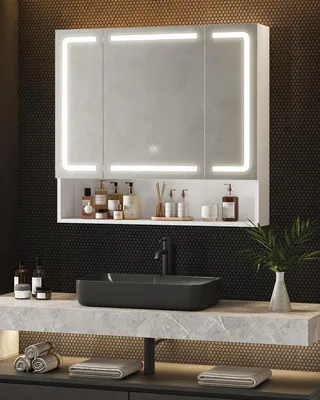 A modern bathroom vanity with a lighted mirror, sink, and accessories.