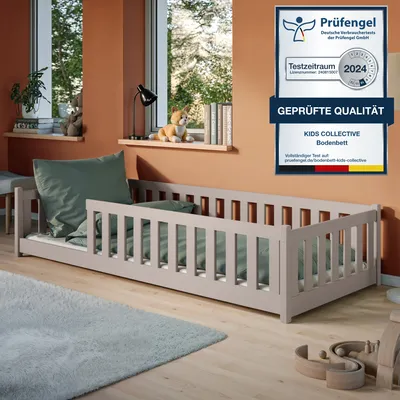 A child's bed with guardrails in a room with orange walls and wooden flooring.