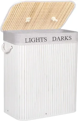 A white bamboo laundry basket with a natural wood lid, open to reveal the interior. The lid has two rope handles. The basket has a grey band around the top with the words "LIGHTS DARKS" printed on it.