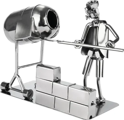 A metal figurine of a construction worker with a cement mixer and bricks.