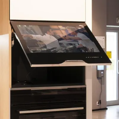 A smart TV integrated into a kitchen cabinet, angled upwards.
