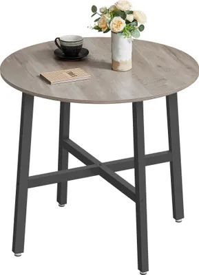 A round dining table with a wood-grain top and dark metal legs, decorated with a vase of flowers and a cup of coffee.