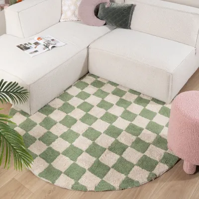 A round checkered rug in front of a sectional sofa with decorative pillows.