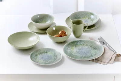 A collection of ceramic tableware, including bowls, plates, and a mug, arranged on a white surface.