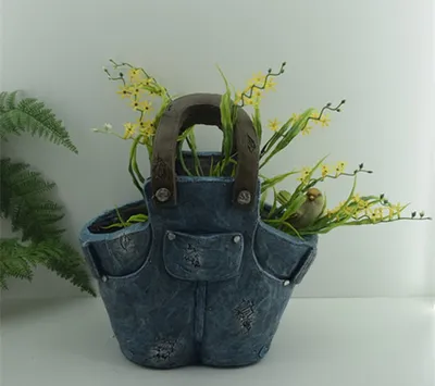 A decorative planter shaped like overalls, filled with artificial plants and a small bird figurine.