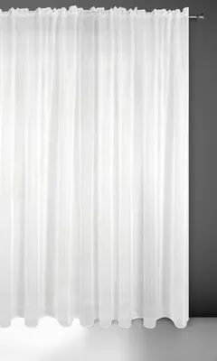 A white sheer curtain hanging against a dark gray wall and a white floor.