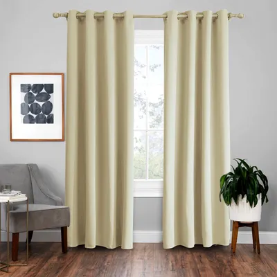 A room interior with beige curtains covering a window, a chair, a small table, and a potted plant.