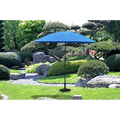 A blue umbrella stands in a lush, green garden with manicured bushes and rocks.
