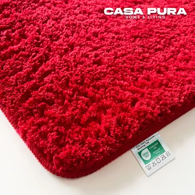 A close-up of a red bath mat with a label attached.