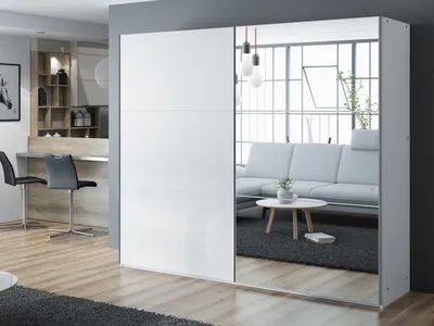 A modern living room with a white wardrobe featuring mirrored doors, reflecting a sofa and coffee table.