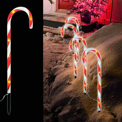 Christmas candy cane lights are placed in the snow outside a house.