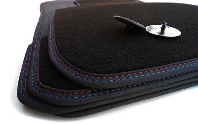 A stack of car floor mats with contrasting stitching.