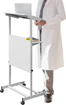 A person in a lab coat stands next to a white, adjustable height podium with a laptop on it.