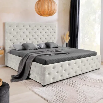 A bedroom scene featuring a tufted bed with storage, a rug, and a pendant light.