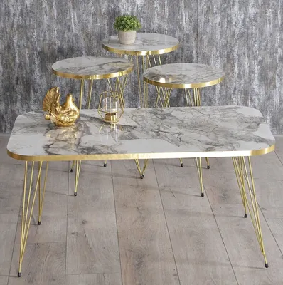 A set of four marble-design nesting tables with gold legs, displayed against a textured gray wall and a wooden floor.