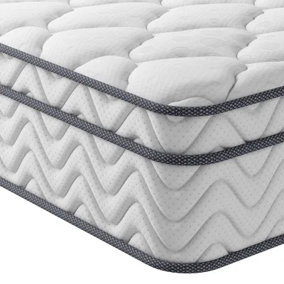 A close-up, angled view of a white mattress with a quilted surface and a dark gray trim along the edges.