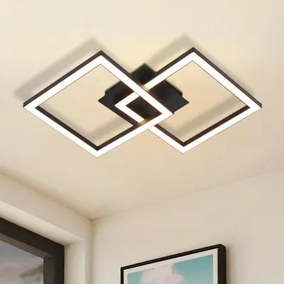 A modern geometric ceiling light fixture with black and white elements, illuminated against a neutral ceiling.