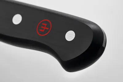 A close-up view of the handle of a knife, showing the brand logo and rivets.