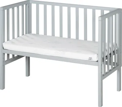 A grey wooden crib with a white mattress on a white background.