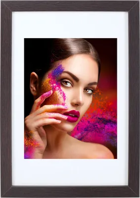 A woman's face is adorned with colorful powder, with her hand reaching towards her cheek.