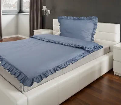 A blue duvet cover and pillowcase set with ruffles on a white bed.