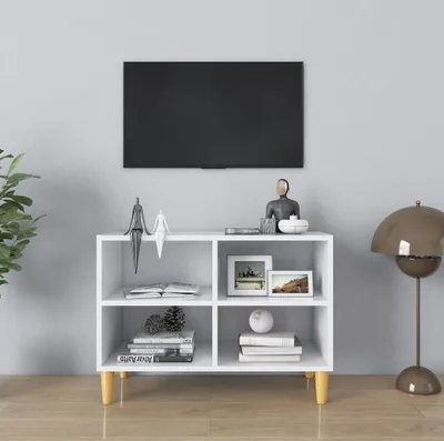 A white TV stand with wooden legs is shown in a room, with a TV mounted on the wall above it.