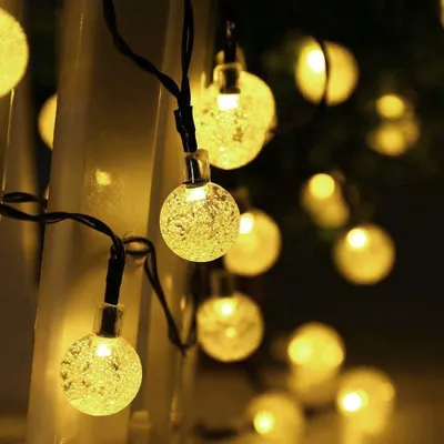 A close-up view of string lights with round, textured bulbs emitting a warm yellow glow.