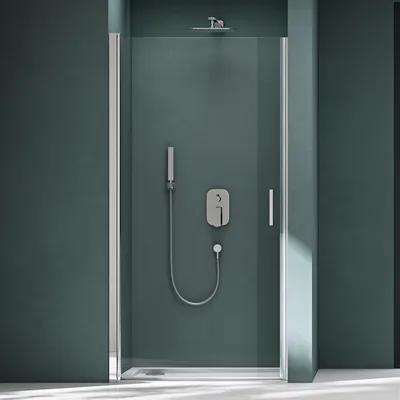 A modern shower enclosure with a single glass door and silver hardware, set against a dark teal wall.