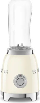 A cream-colored Smeg mini-stand mixer with a clear blending cup attached.