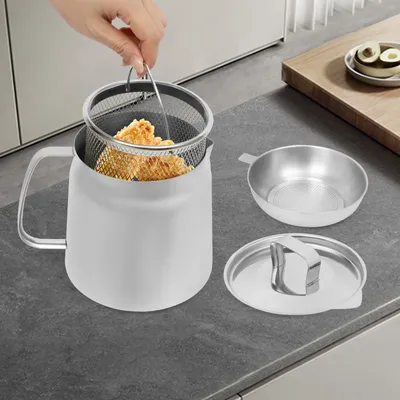 A hand is shown lifting a mesh basket filled with fried food out of a stainless steel pot on a kitchen counter.