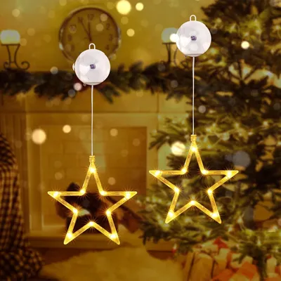 Two star-shaped LED lights hanging in front of a Christmas tree and fireplace.