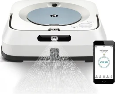 A white robot vacuum cleaner is shown spraying water onto the floor, with a smartphone displaying a cleaning app next to it.