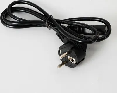 A black power cord with a European plug and a C13 connector lies on a white background.