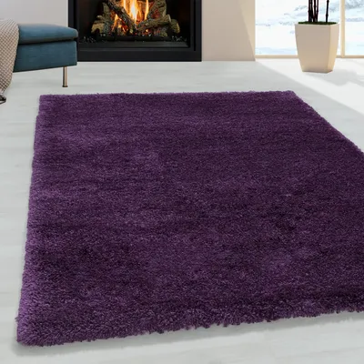 A plush purple rug is laid out on a light-colored floor in front of a fireplace.
