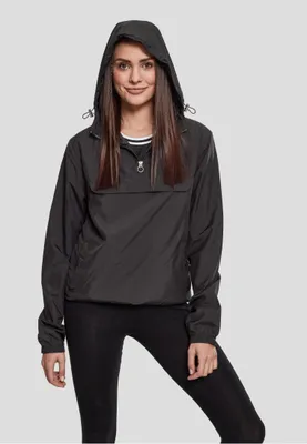 A woman wearing a black windbreaker and black leggings against a plain gray background.