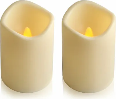 Two cream-colored LED candles with flickering yellow flames are shown side-by-side against a white background.