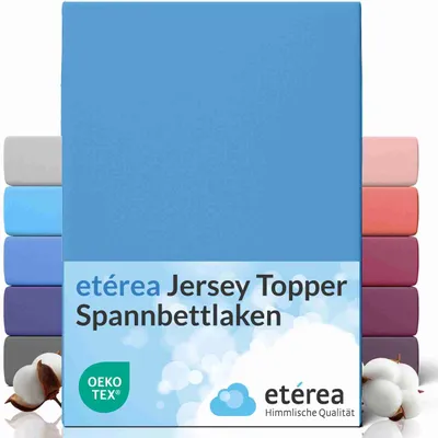 A stack of folded fitted sheets in various colors, with the main product in a bright blue color prominently displayed. The image also includes cotton bolls and branding.