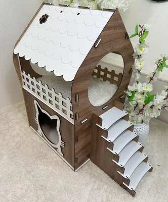 A multi-level cat house with stairs, made of wood and white accents, placed on a white carpet.