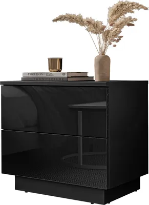 A black high-gloss nightstand with two drawers, decorated with dried flowers in a vase and books.
