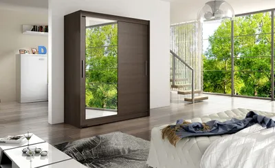 A bedroom scene with a large wardrobe, bed, and a window overlooking trees.