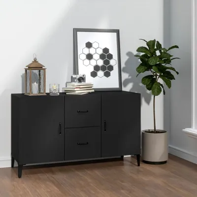 A black sideboard with decorative items and a plant in a pot, set against a white wall and wooden floor.
