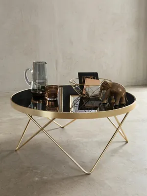 Eleganter runder Couchtisch mit schwarzer Glasplatte und geometrischem Gestell aus mattem Gold. Das 82 cm breite Design-Möbelstück vor weißem Hintergrund zeigt seine klare Silhouette._#sku_SAFWL5.786#