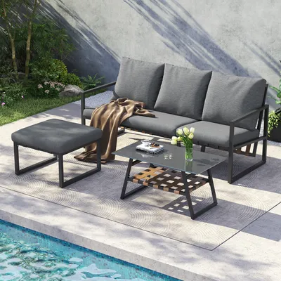 An outdoor furniture set including a sofa, coffee table, and ottoman is placed on a patio next to a swimming pool.