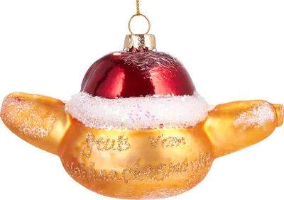 A close-up studio shot of a Christmas ornament shaped like a sausage in a bun, wearing a Santa hat.