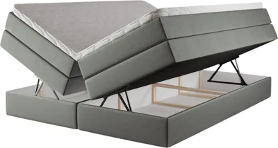 A gray upholstered bed frame with two mattresses, one of which is lifted to reveal storage space underneath.