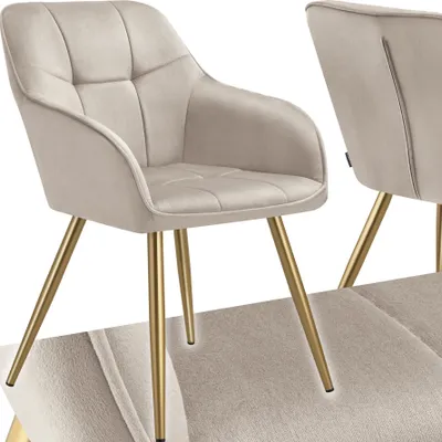 A close-up studio shot of a beige upholstered dining chair with gold legs.