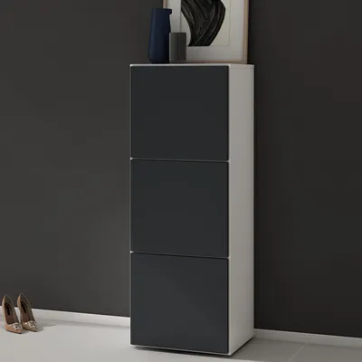 A modern shoe cabinet with three drawers against a dark gray wall.