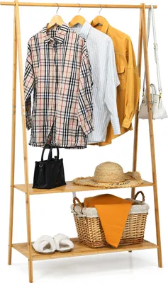 A bamboo clothing rack with clothes and accessories displayed on it.
