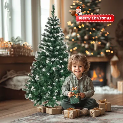 A young boy sits on the floor next to a Christmas tree, surrounded by presents.